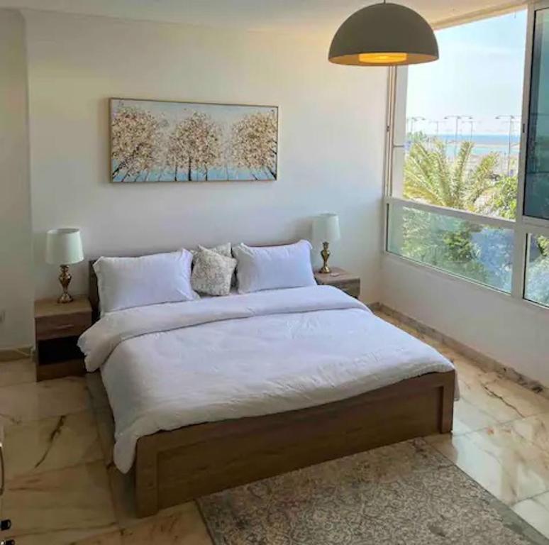 a bedroom with a bed and a large window at Luxurious Apartment Partial Sea View in Jeddah