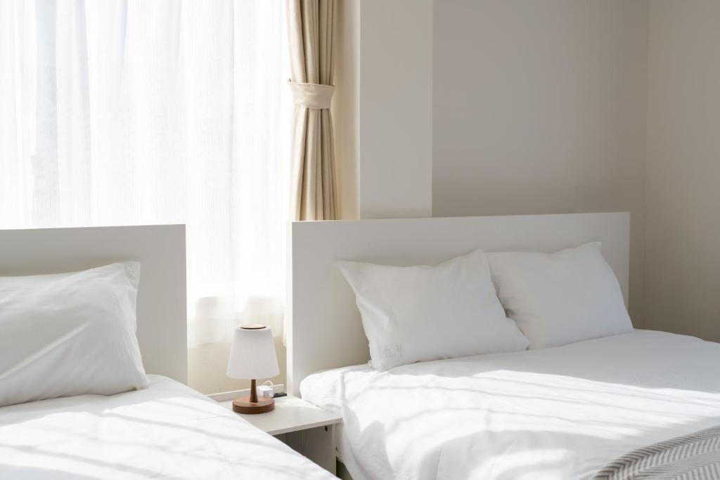 - 2 lits blancs dans une chambre avec fenêtre dans l'établissement ILIMA Higashi Nakano 新宿から電車で5分 東中野駅まで徒歩2分 最大4人 洗濯機 ダイニングキッチン 電子レンジ, à Tokyo