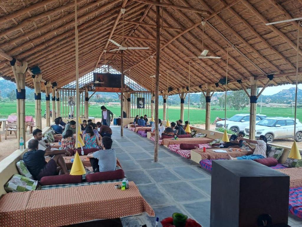 een groep mensen op banken in een paviljoen bij Rasta Cafe Hmpi in Hampi