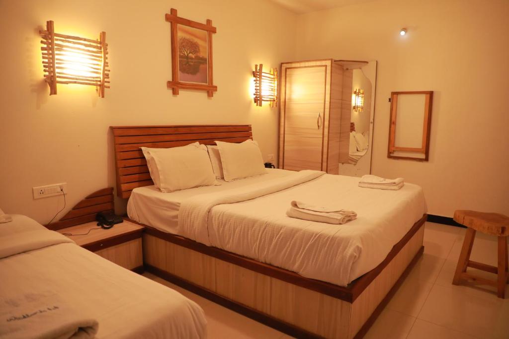 1 Schlafzimmer mit 2 Betten mit weißer Bettwäsche und einem Spiegel in der Unterkunft The Woodlands Residency- Unmarried and stag groups not allowed in Udagamandalam