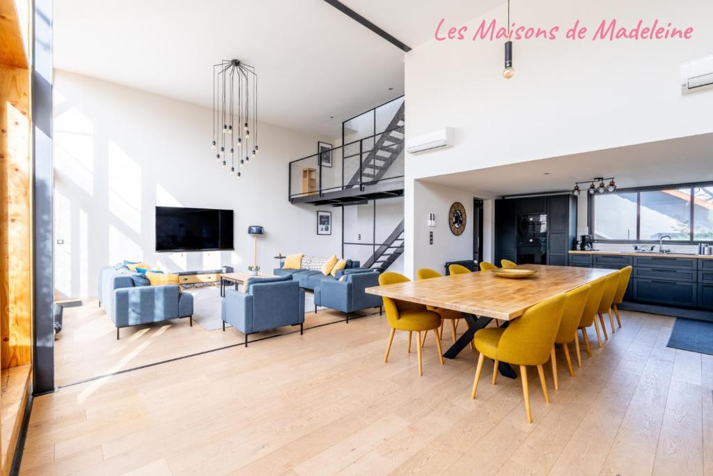 une salle à manger et un salon avec une table en bois et des chaises jaunes dans l'établissement Le Studio Nantais - Loft moderne avec rooftop, à Nantes