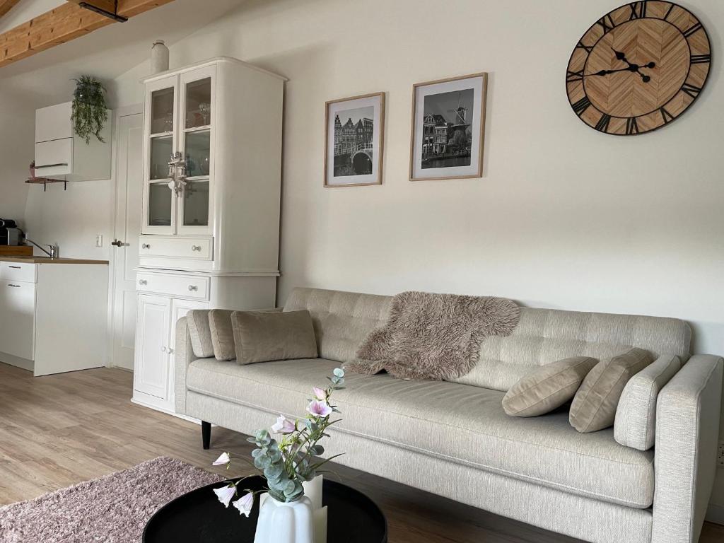 uma sala de estar com um sofá e um relógio na parede em Veldhorst Apartments em Leiden