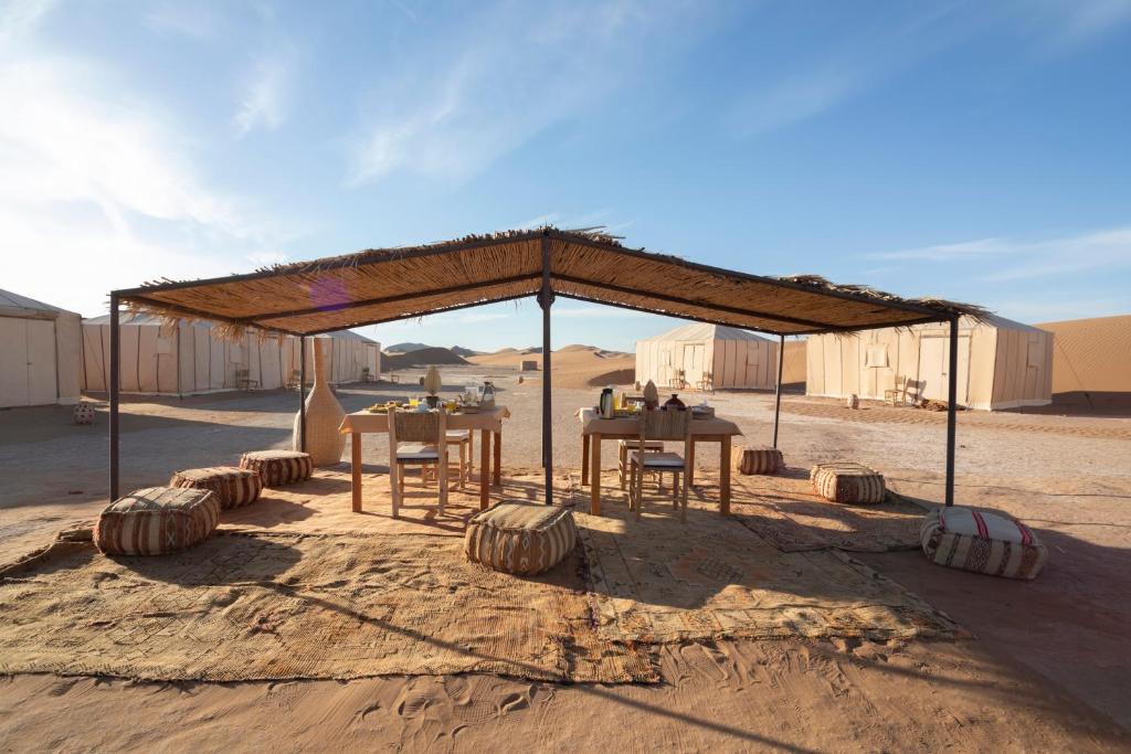 a tent with tables and chairs in the desert at Erg Chegaga Desert Luxury Camp in El Gouera