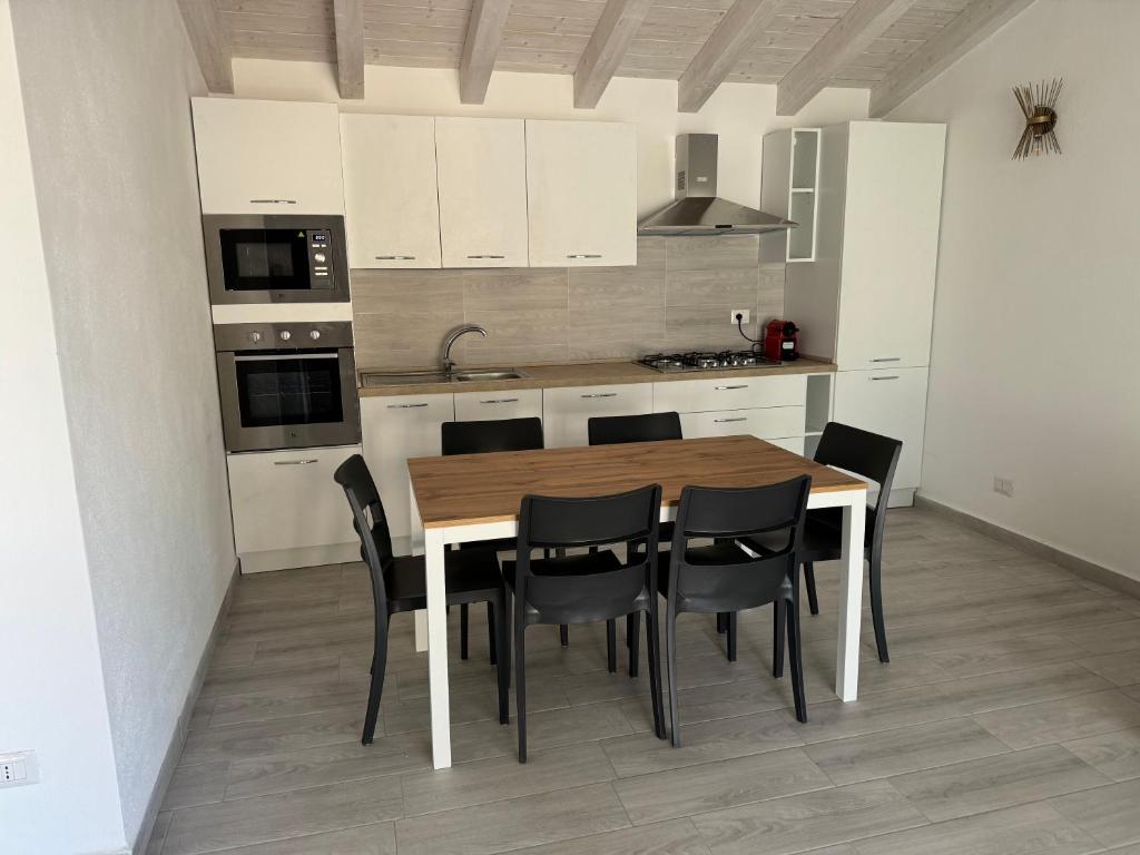 a kitchen with a wooden table and black chairs at Villetta 2 La Caletta in La Caletta