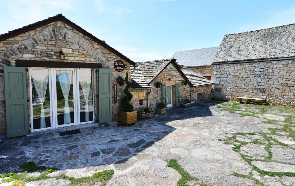 uma vista exterior para uma casa de pedra com um pátio em Gîte le Four d'Odilon em La Malène