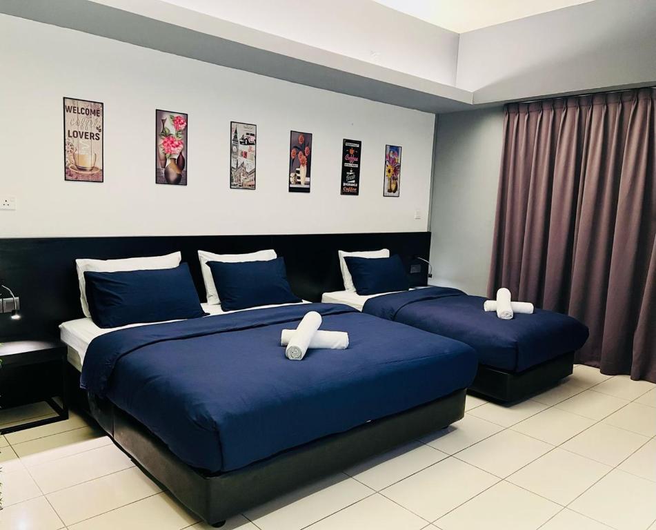 2 camas en una habitación de hotel con sábanas azules en M Suite Homestay, Aeropod Sovo Kota Kinabalu, en Tanjong Aru