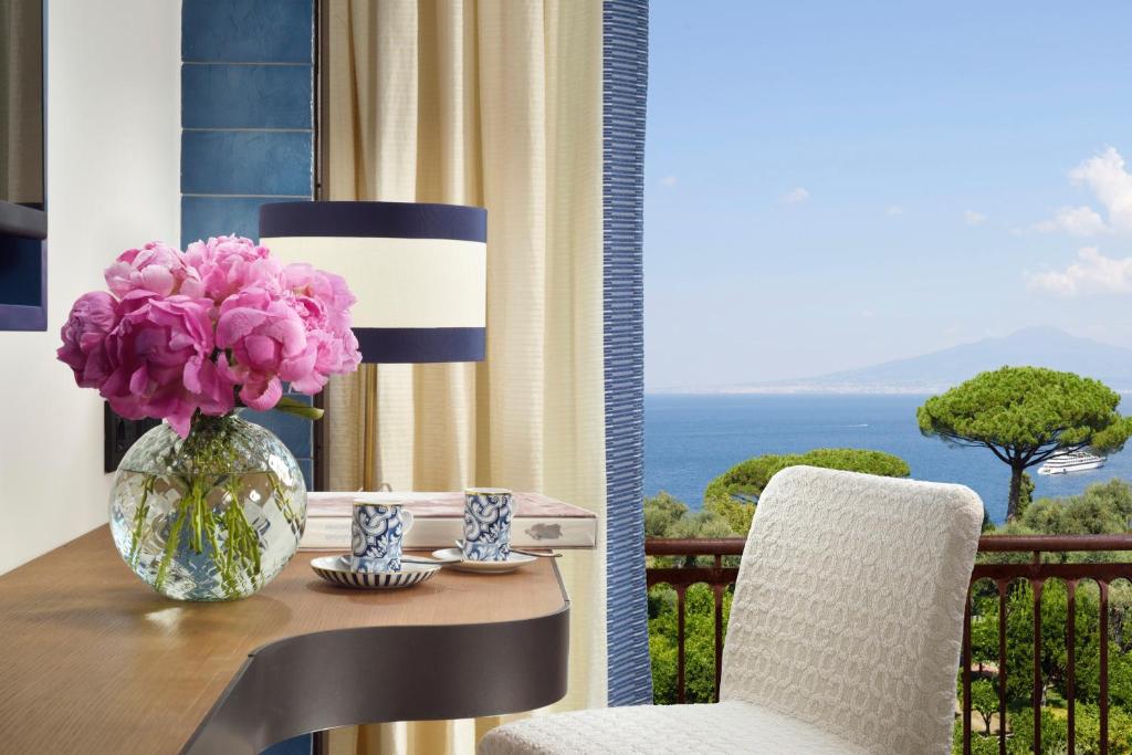 un tavolo con un vaso di fiori rosa su un balcone di Ara Maris a Sorrento
