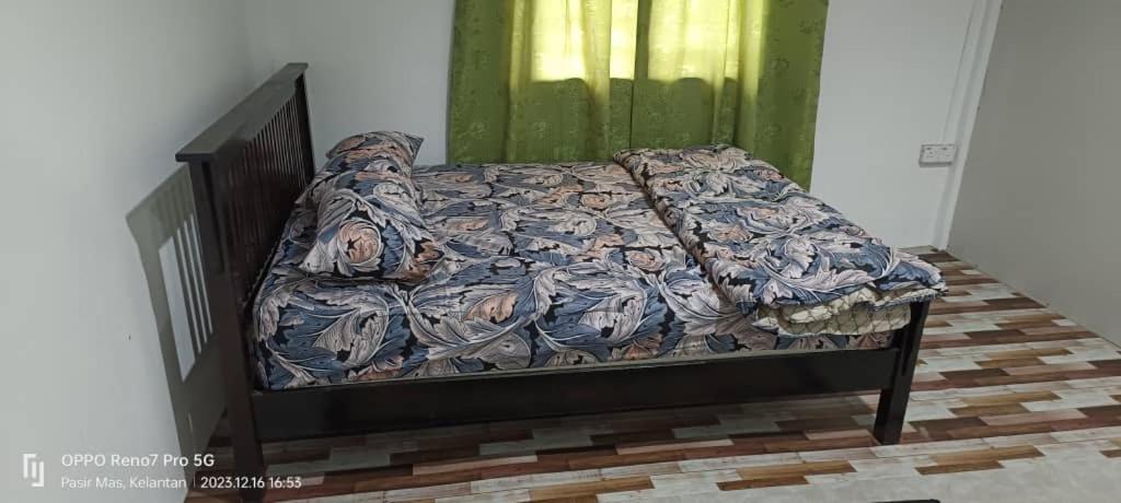 uma cama num quarto com uma parede verde em Sobey Laris Homestay TENDONG em Pasir Mas