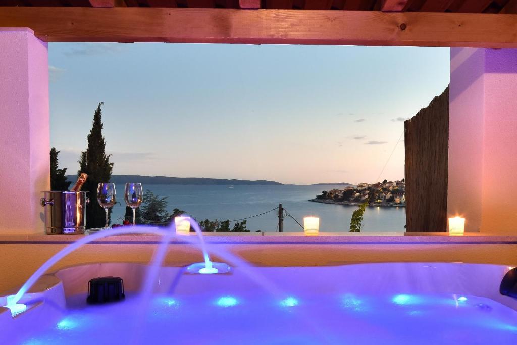 a bath tub with a window with a view of the ocean at Villa Maestral with pool Ciovo in Trogir