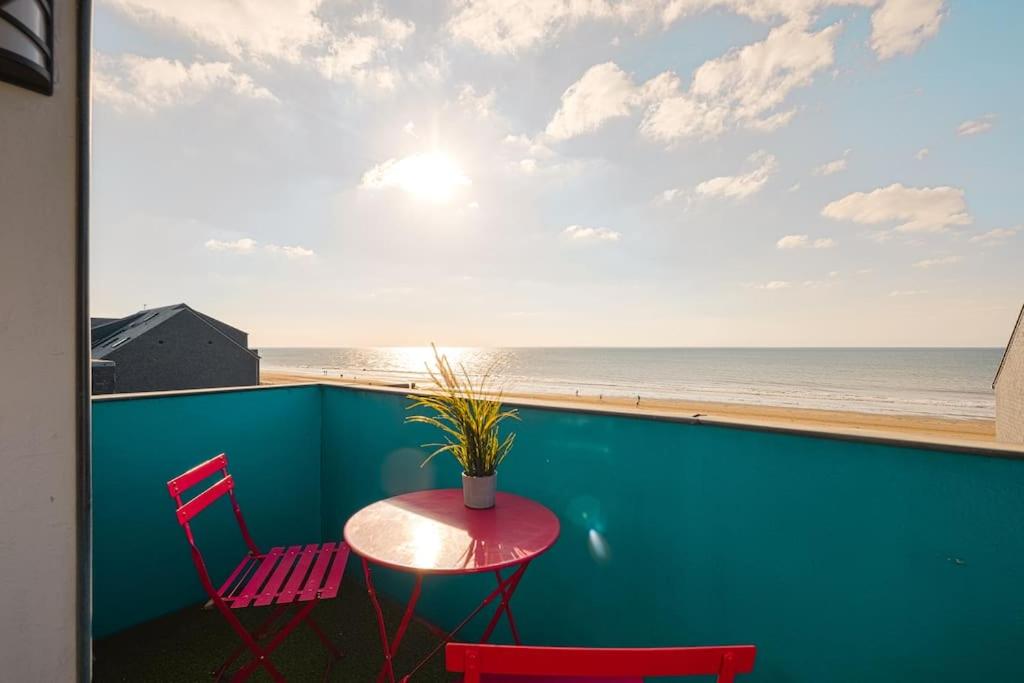 een tafel en 2 stoelen op een balkon met uitzicht op het strand bij Les Dunes - Duplex - 6 personnes in Jullouville-les-Pins