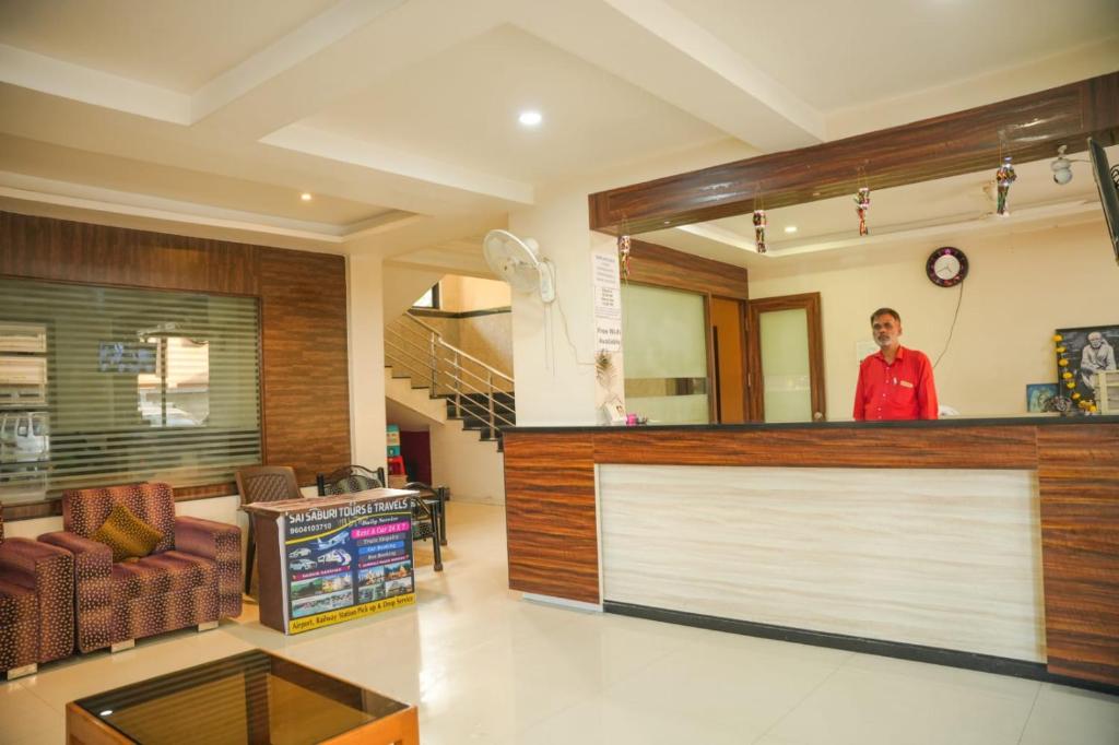 a man standing behind a counter in a lobby at Hotel Sachidanand in Shirdi