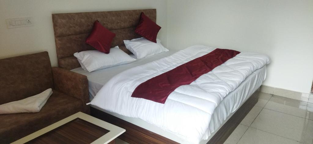 um quarto com uma cama grande com lençóis brancos e almofadas vermelhas em Hotel Lake View Paradise em Uttarkāshi