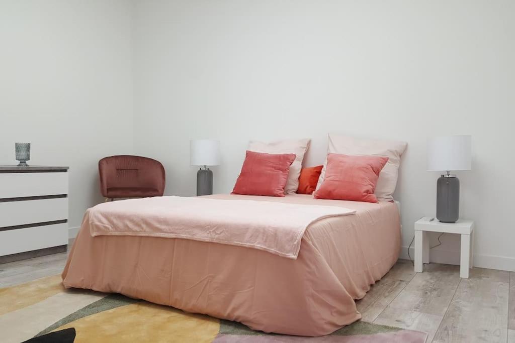 Schlafzimmer mit einem Bett mit rosa Bettwäsche und einem Stuhl in der Unterkunft Aux Docks Rémois in Bétheny