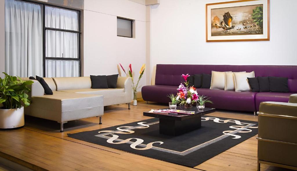 a living room with a purple couch and a coffee table at Hospedium Hotel Urban Bogotá Javeriana in Bogotá