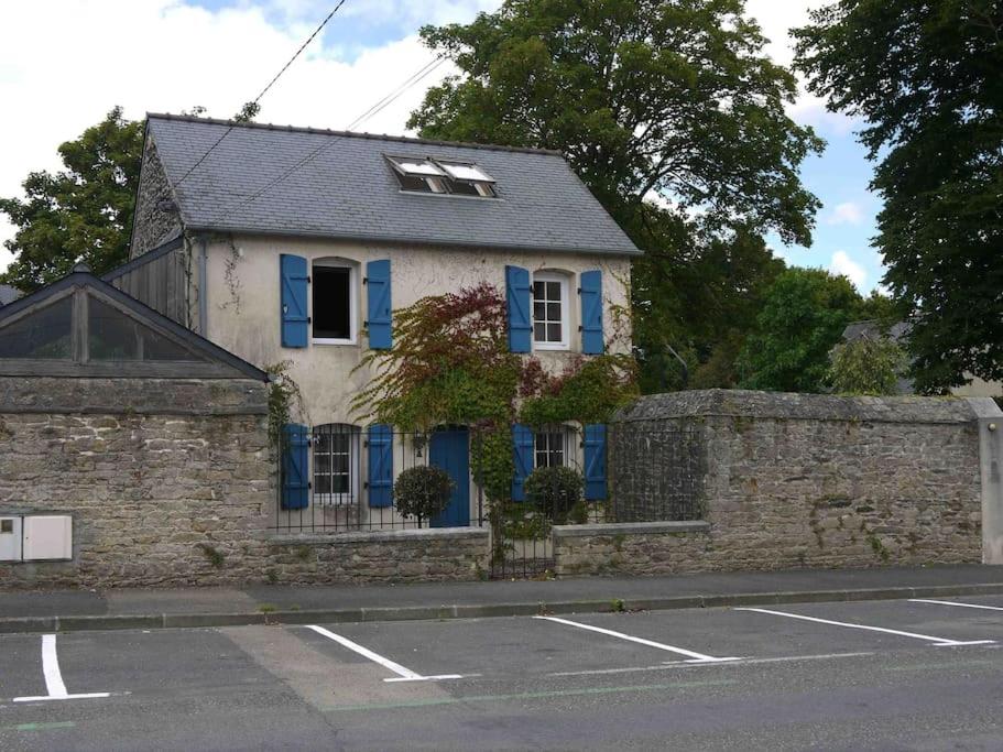 dom z niebieskimi okiennicami i kamienną ścianą w obiekcie Maisonnette - Centre Landerneau w mieście Landerneau