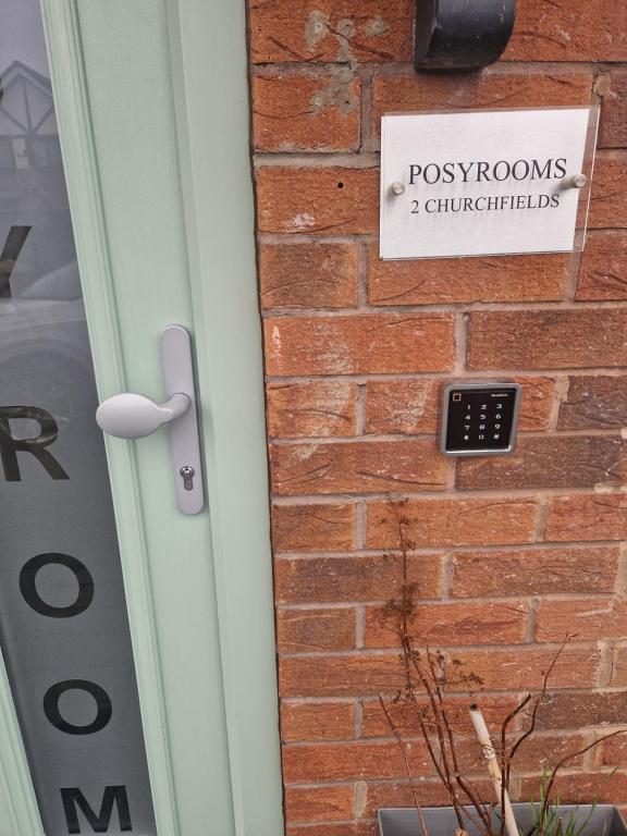 eine Tür mit einem Schild an der Seite einer Ziegelmauer in der Unterkunft Posyrooms in Manchester