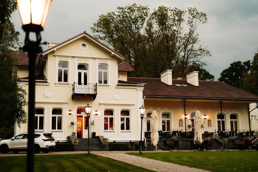 une maison blanche avec une voiture garée devant elle dans l'établissement Dwór na Wolicy, à Dębica