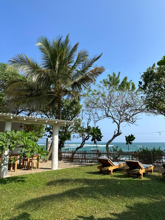 um parque com bancos e uma palmeira e o oceano em MIRISSA Reef Serenity em Mirissa