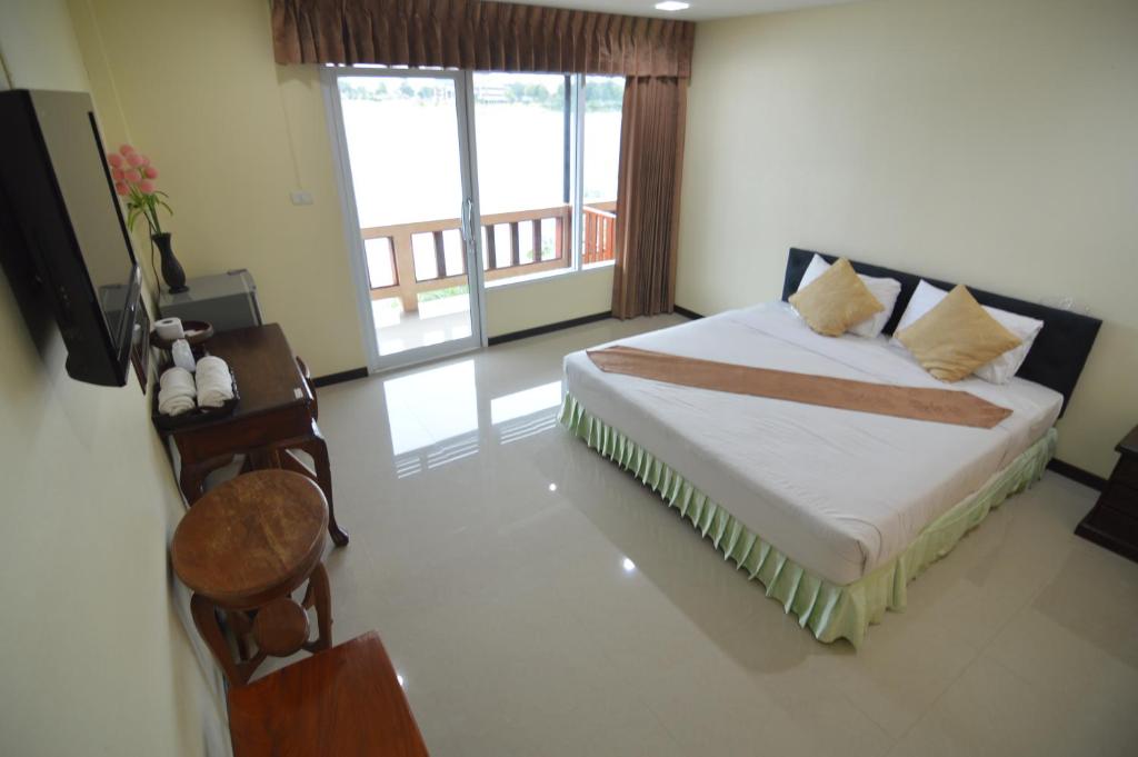 a bedroom with a bed and a table and a window at Techno Riverview Resort in Kamphaeng Phet