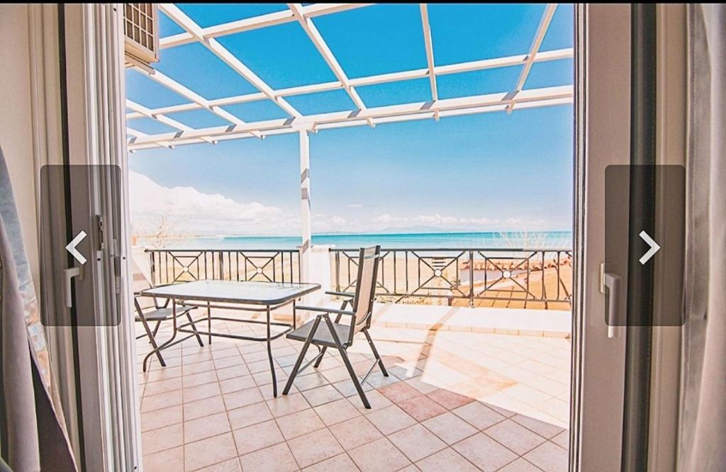 un balcone con tavolo e sedie e vista sull'oceano. di Κatakolo Luxury Seaside House & Garden a Katakolo