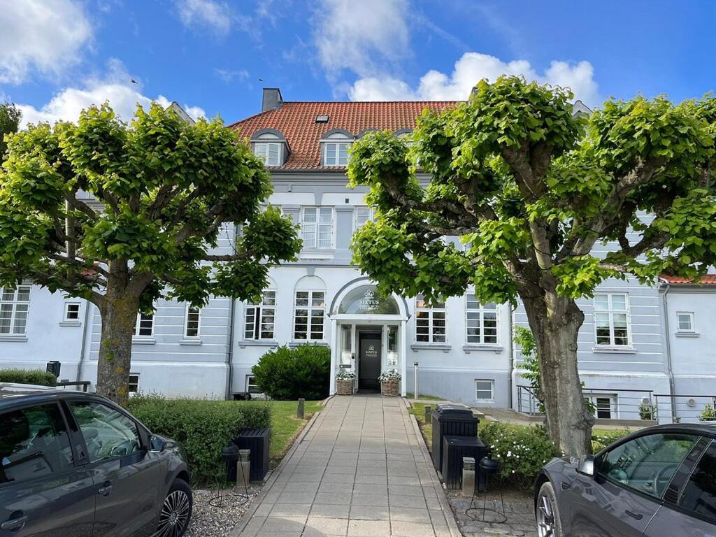 un grand bâtiment blanc avec des voitures garées devant lui dans l'établissement Sixtus Sinatur Hotel & Konference, à Middelfart