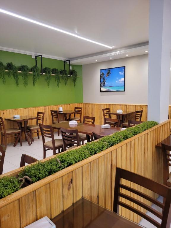 un restaurante con mesas y sillas de madera y paredes verdes en Pousada Concha Dourada en Maragogi