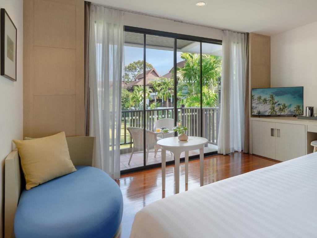 a bedroom with a bed and a table and a balcony at Amari Koh Samui in Chaweng