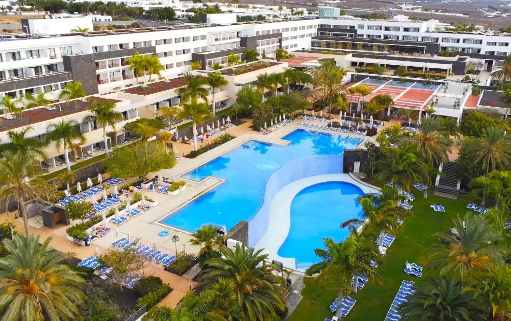 an aerial view of a resort pool with palm trees at Hotel Costa Calero Thalasso & Spa in Puerto Calero
