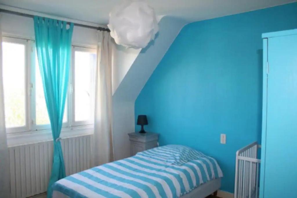 een blauwe slaapkamer met een bed en een blauwe muur bij Le Goéland in Sarzeau