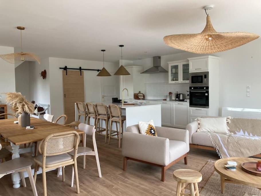 ein Wohnzimmer und eine Küche mit einem Sofa und einem Tisch in der Unterkunft St Malo à 15 Min et 10 Min de Dinard in Pleurtuit