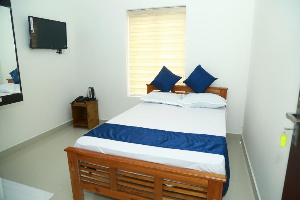 a bedroom with a bed with blue pillows and a television at AIRPORT COCHIN ROYAL RESIDENCY in Ernakulam