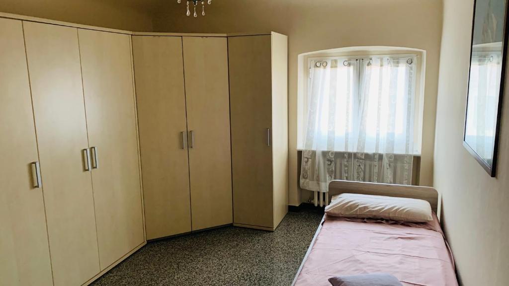 a bedroom with a bed and a cabinet and a window at Casa Vacanze Libarna Outlet in Serravalle Scrivia