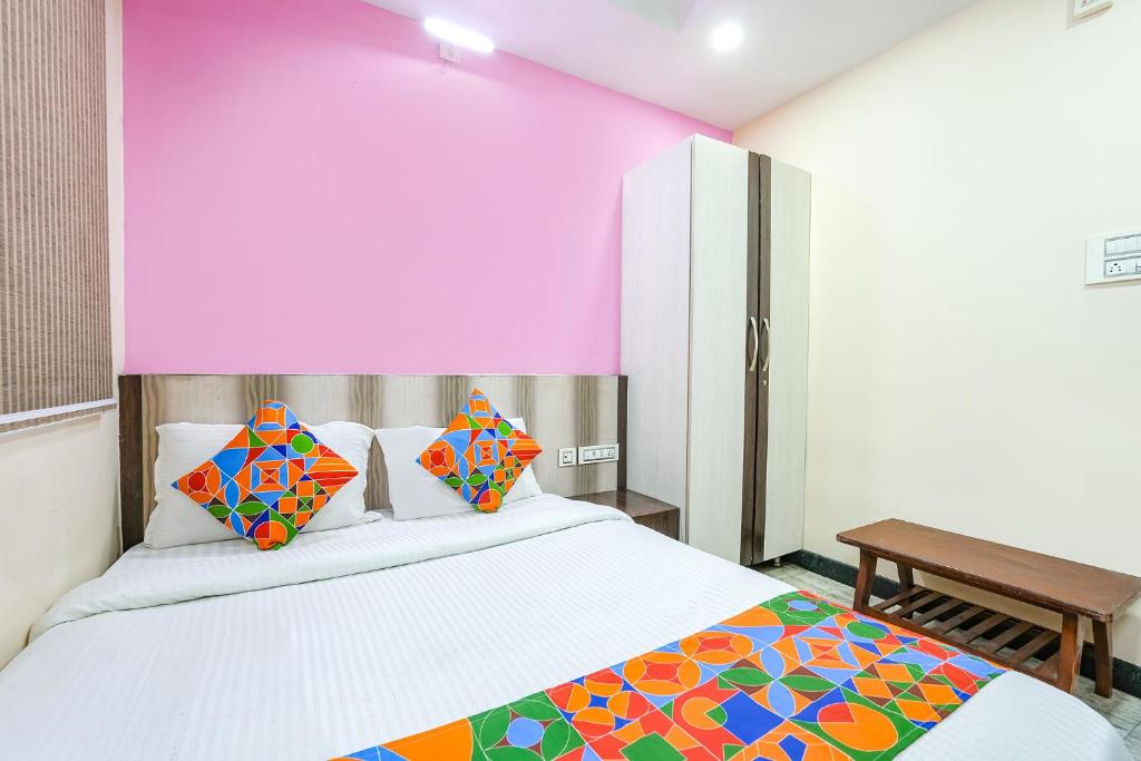 a bedroom with a white bed with colorful pillows at FabExpress Raj Supreme Residency in Chennai