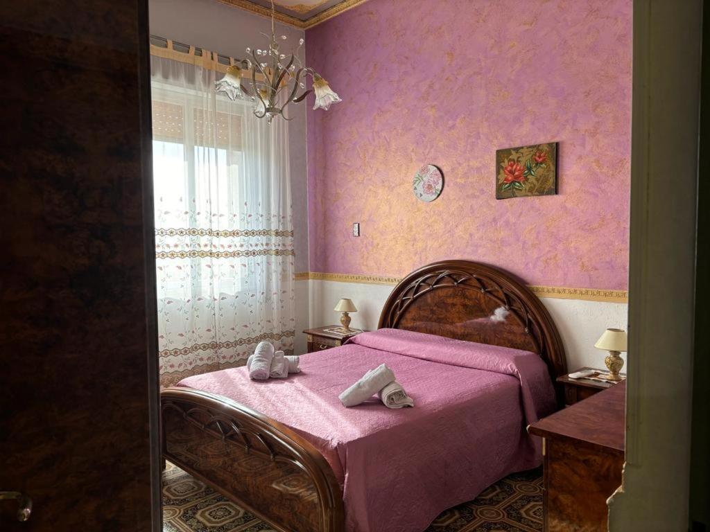 um quarto rosa com uma cama com toalhas em House Giulia al Borgo Marinaro em Avola
