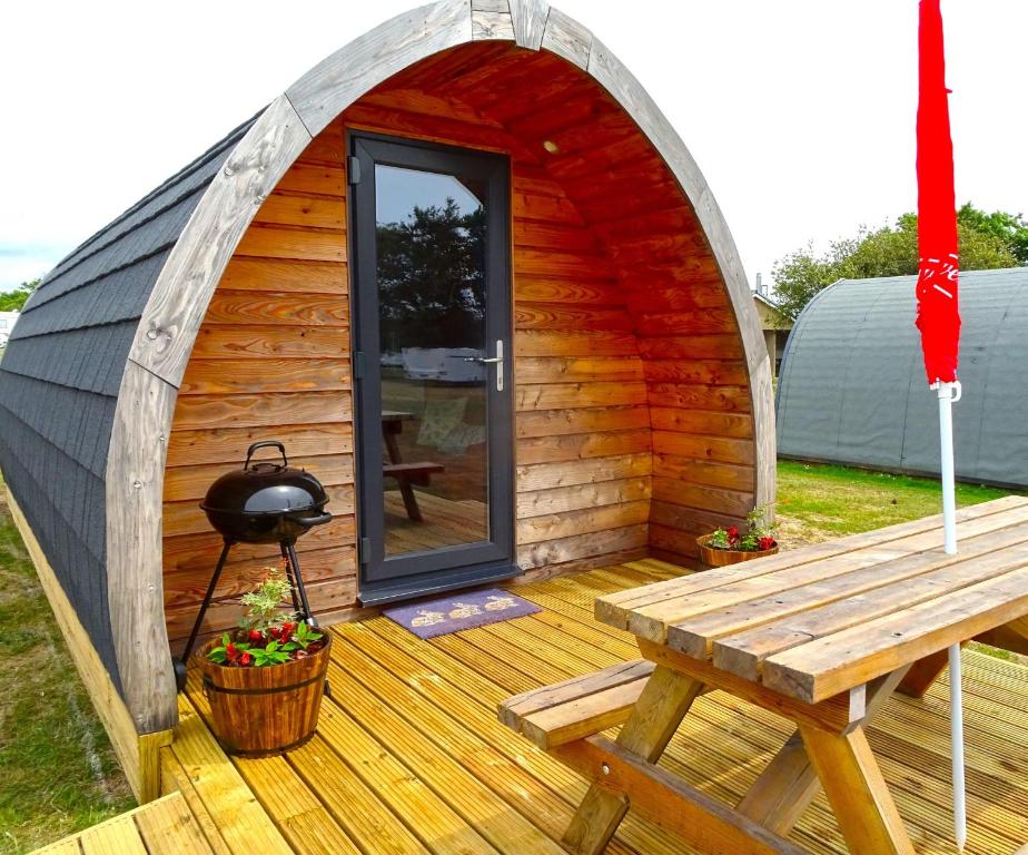 uma tenda com um deque de madeira com um banco e uma mesa em Gateway Resort En-Suite Glamping Pod em Llanelli