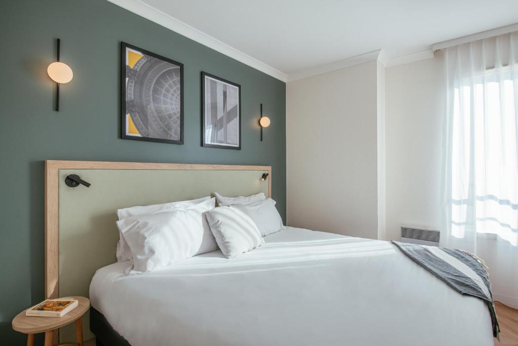 a bedroom with a large white bed with blue walls at Aparthotel Adagio Paris Buttes Chaumont in Paris