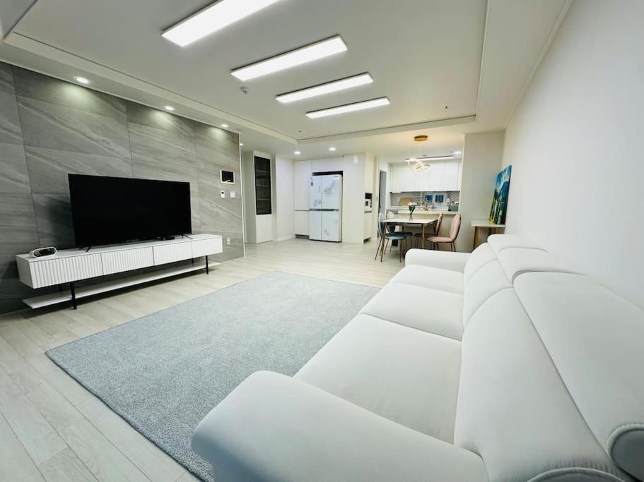 a living room with white furniture and a flat screen tv at JY House 1 in Busan