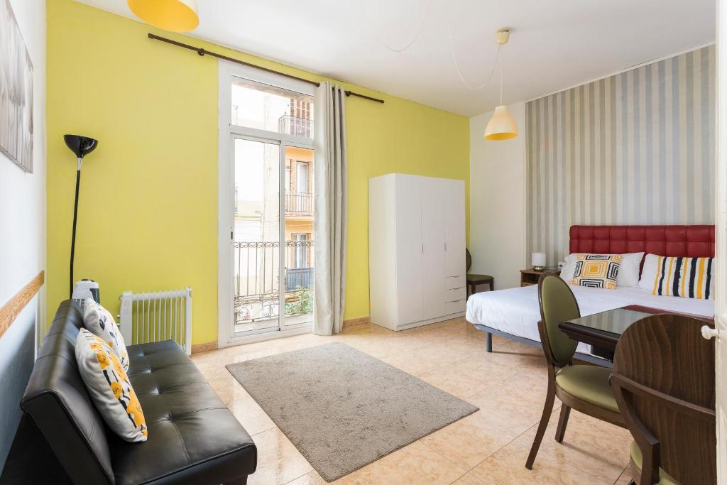 a bedroom with a bed and a table and a couch at Apartaments Clot-Sant Martí in Barcelona