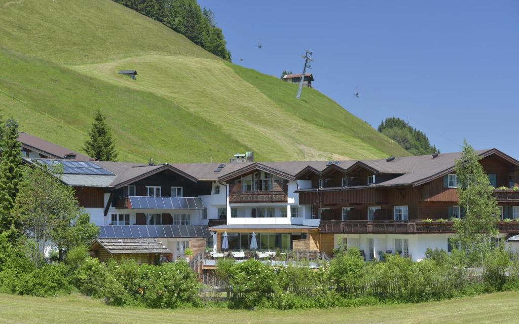 a hotel with a green hill in the background at Naturhotel Lärchenhof in Mittelberg