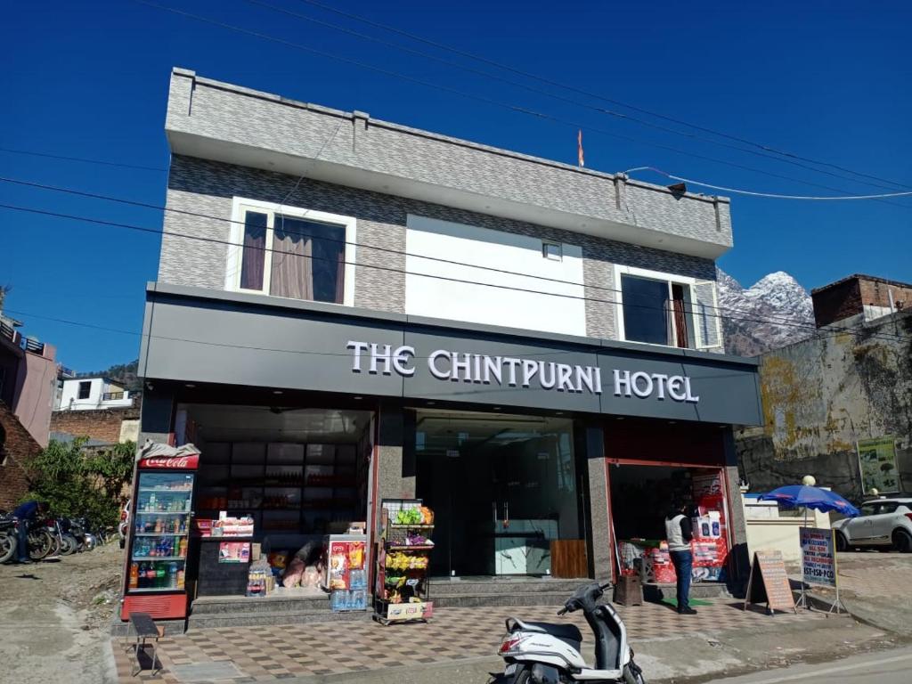een gebouw met een motor die ervoor geparkeerd staat bij The Chintpurni Hotel in Katra