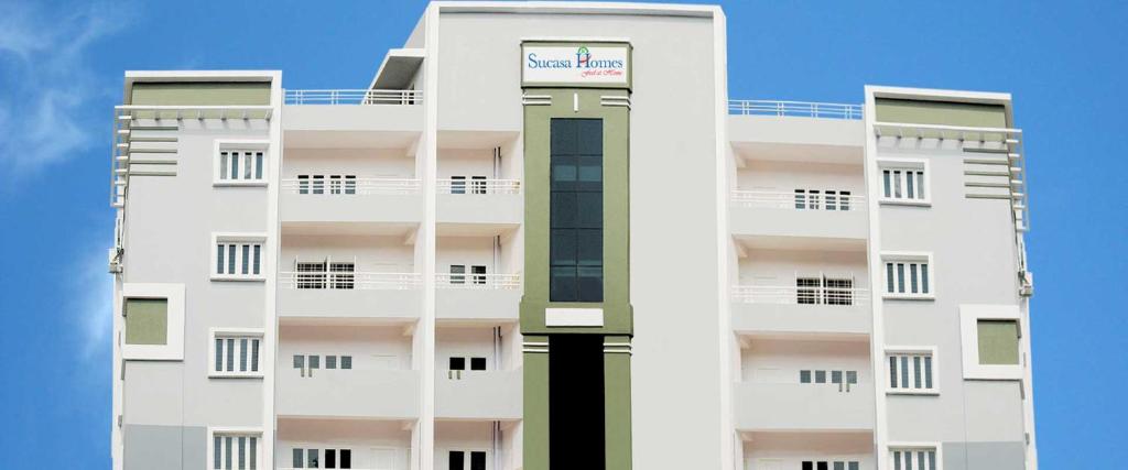 a tall white apartment building with a clock tower at Sucasa homes (HOME AWAY FROM HOME GUESTS SERVICES in Hyderabad