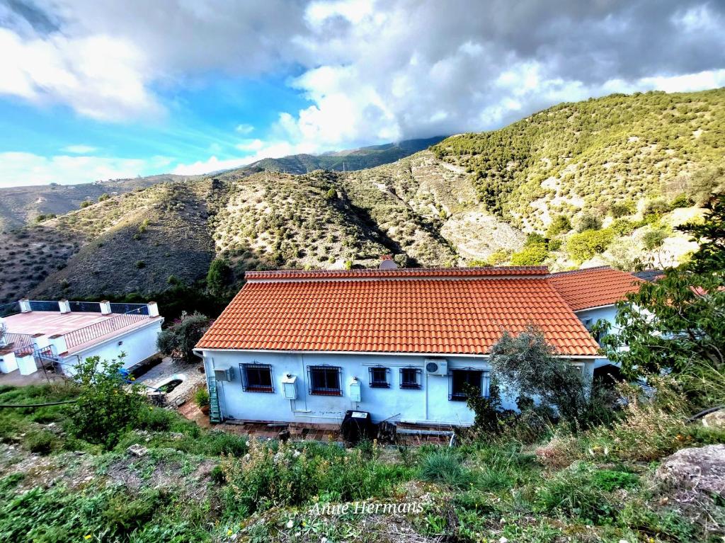 een wit huis met een oranje dak op een berg bij Finca Floretta in Canillas de Albaida