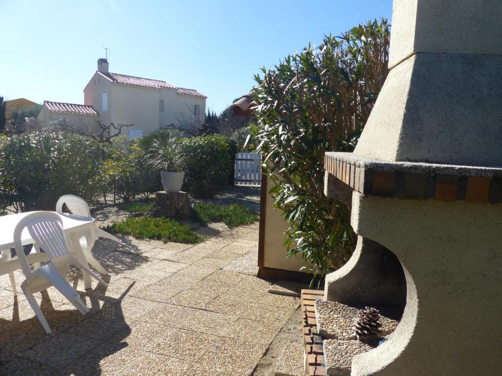 d'une terrasse avec une chaise blanche et une table. dans l'établissement St Cyprien Maison de vacances climatisée avec jardin, à Saint-Cyprien