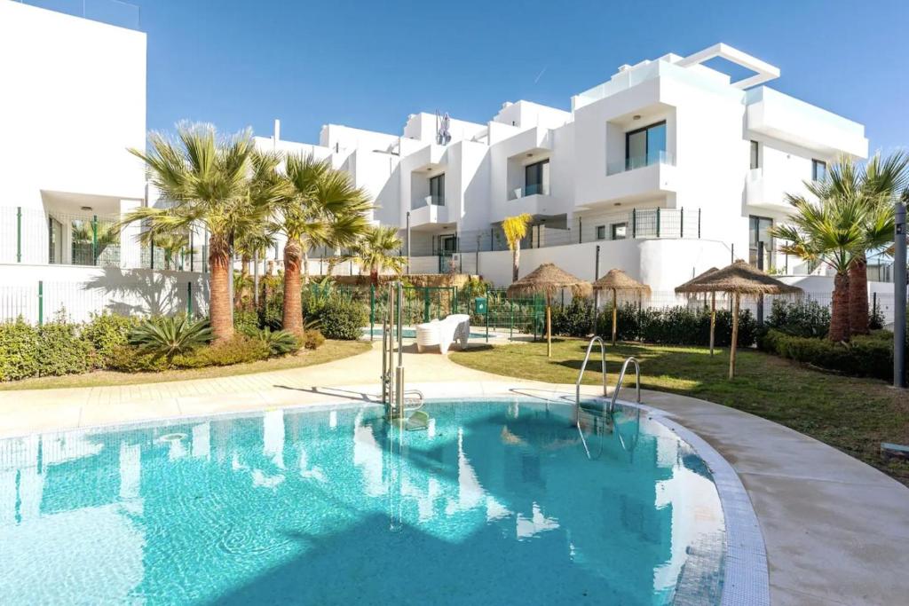 una piscina frente a un edificio blanco en Beach terraced house close town, en Fuengirola