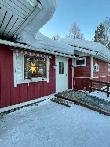 a red house with snow on the side of it at Tiitun Tupa Ivalo in Ivalo