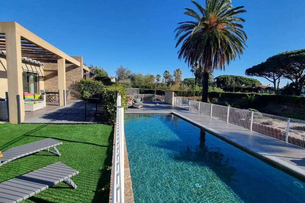 une piscine devant une maison avec un palmier dans l'établissement Chez K&D Appartement, piscine, mer 150m, à Grimaud