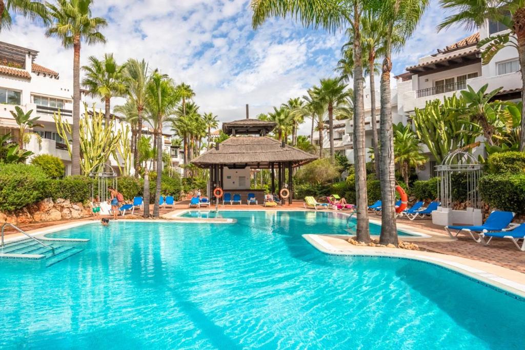 een zwembad in een resort met palmbomen en een prieel bij Beachside Luxury 2 bedroom apartment, Puerto Banus in Marbella