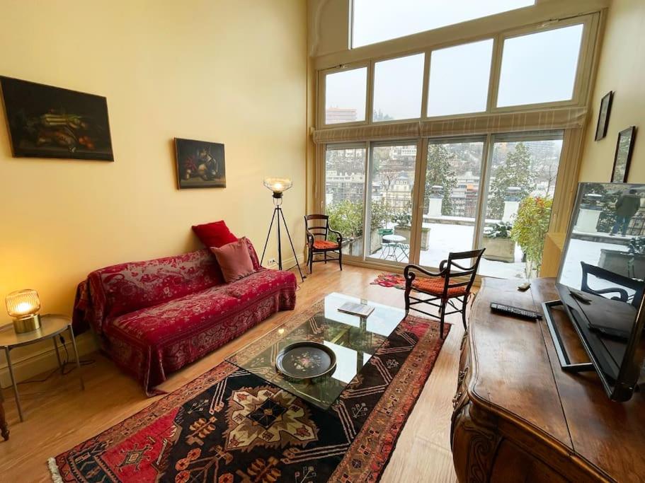 ein Wohnzimmer mit einem roten Sofa und einem Tisch in der Unterkunft Merveilleux Duplex Royat Vue in Royat