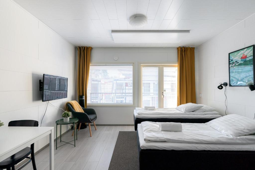 Cette chambre comprend deux lits, une table et un bureau. dans l'établissement Hiisi Homes Sipoo Söderkulla, à Söderkulla