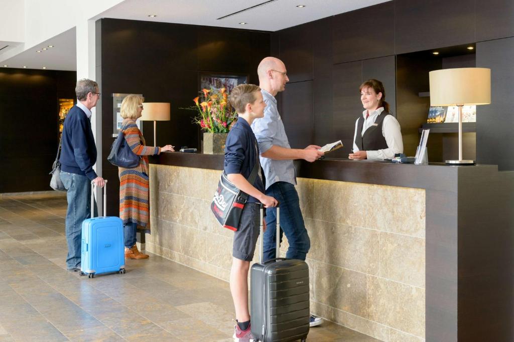 a group of people standing at a counter with luggage at ATLANTIC Hotel Lübeck in Lübeck